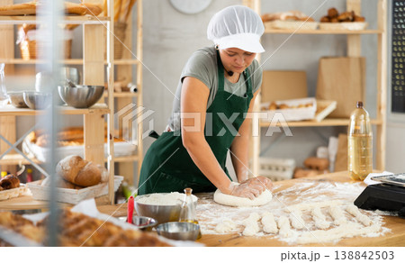 Woman works in bakery as baker, kneads dough, works with flour. Woman works in bakery as baker, kneads dough, works with flour. 138842503