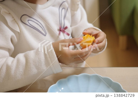 家で水色のお皿のみかんを食べる子供の手元 138842729