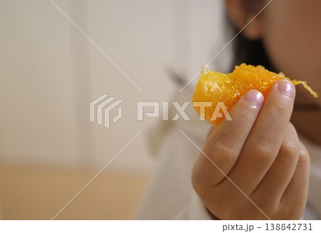 みかんを一房手に持って食べる子供の手元 みかんを一房手に持って食べる子供の手元 138842731