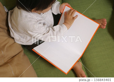 家の緑色のソファに座って絵本をめくる子供の俯瞰 138843401