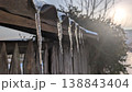 Bright sunlight causes delicate melting of icy fence adornments 138843404