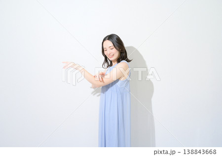 白背景で腕に日焼け止めを塗る日本人女性のビューティイメージ 138843668
