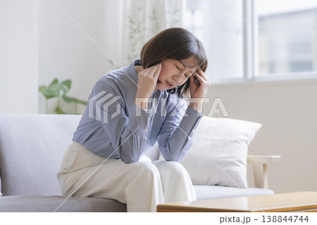 ソファに座り頭を抱えるアラフィフの女性 138844744
