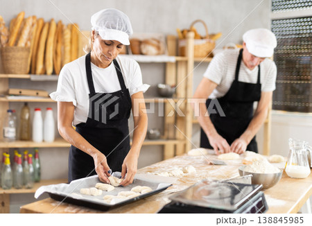 Elderly man and woman make and fold pieces of dough 138845985