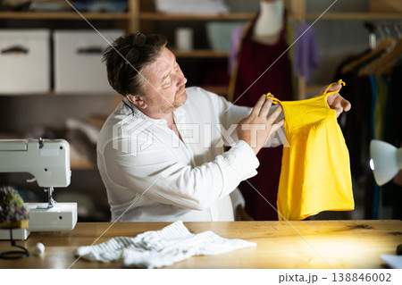 Man seamstress sewing manufactures childrens clothing 138846002