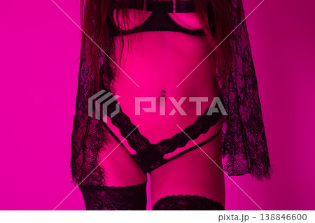 Sensual woman in black lace lingerie with belly piercing in magenta neon light 138846600