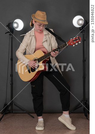 Young woman guitarist playing guitar, standing full length on stage, concentration and looking down Young woman guitarist playing guitar, standing full length on stage, concentration and looking down 138846822
