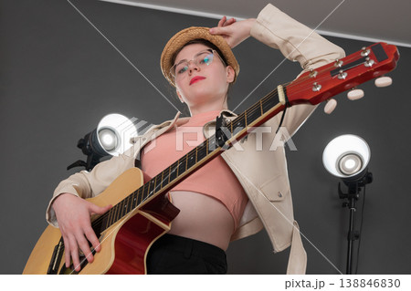Self assured female guitarist holding six string acoustic guitar and looking at camera Self assured female guitarist holding six string acoustic guitar and looking at camera 138846830