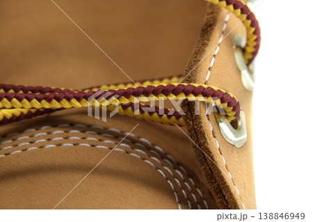 Close-up detail of a tan leather boot with a braided yellow and burgundy shoelace 138846949