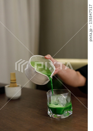 fresh matcha tea, green tea pouring on a glass on wooden table. fresh matcha tea, green tea pouring on a glass on wooden table. 138847517