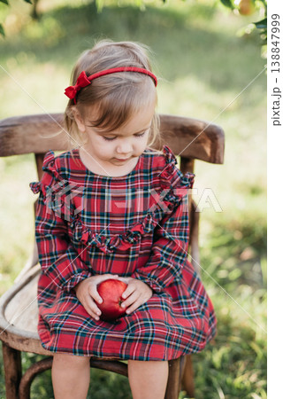 Child picking apples on farm in autumn. Little girl playing in apple tree orchard. Healthy nutrition. Cute little girl eating red delicious apple. Apple picking. Child picking apples on farm in autumn. Little girl playing in apple tree orchard. Healthy nutrition. Cute little girl eating red delicious apple. Apple picking. 138847999