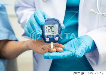 Asian doctor using digital glucose meter for check sample blood sugar level to treatment diabetes. 138851147