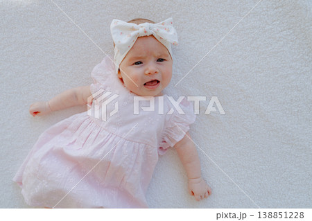 Baby girl lying on soft surface and moving naturally. Candid lifestyle shot showing early development and childhood activity. Baby girl lying on soft surface and moving naturally. Candid lifestyle shot showing early development and childhood activity. 138851228