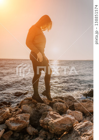 Woman, Ocean, Sunset. Contemplative woman standing on a rocky ocean shore during beautiful golden hour with ample copy space. Woman, Ocean, Sunset. Contemplative woman standing on a rocky ocean shore during beautiful golden hour with ample copy space. 138851574