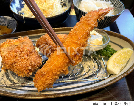 海老フライを箸でつまんだアップ ─ ミックスフライ定食 138851965