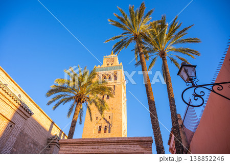 Kutubiyya Mosque is the largest mosque in Marrakesh, Morocco. Its tall tower rises above palm trees during bright daylight. Visitors explore the area around the mosque. Kutubiyya Mosque is the largest mosque in Marrakesh, Morocco. Its tall tower rises above palm trees during bright daylight. Visitors explore the area around the mosque. 138852246