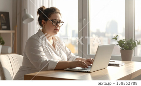 Young woman working on laptop during train travel at sunset. Professional digital nomad lifestyle with golden sun flare, remote working, and commuter journey in modern railway carriage interior 138852789