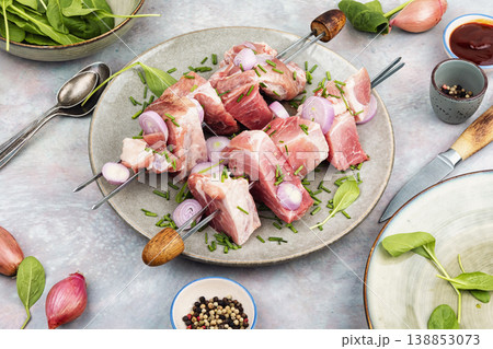 Uncooked pork kebabs with onion on skewers 138853073