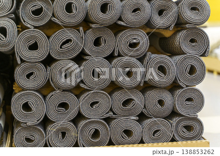 Industrial carpet production and storage with large rolls of textile flooring. Manufacturing process of various synthetic carpets in a warehouse or factory facility. 138853262