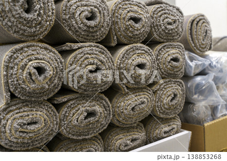 Industrial carpet production and storage with large rolls of textile flooring. Manufacturing process of various synthetic carpets in a warehouse or factory facility. Industrial carpet production and storage with large rolls of textile flooring. Manufacturing process of various synthetic carpets in a warehouse or factory facility. 138853268