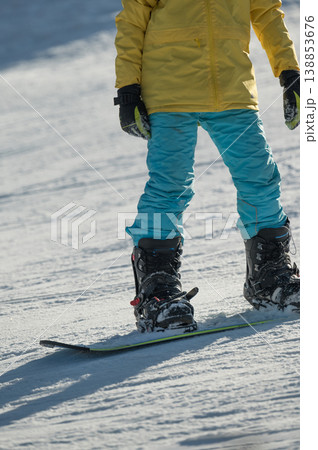 Brightly dressed skier enjoys a thrilling day on the snowy slopes, expertly balancing on a snowboard while surrounded by winter wonderland sights and sounds, immersed in excitement 138853676