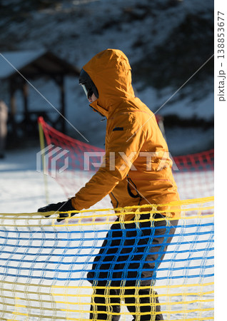 Gliding through the snowy slopes while wearing a vibrant yellow jacket, a joyful figure embraces winter sports at an alpine resort during a sunny afternoon 138853677