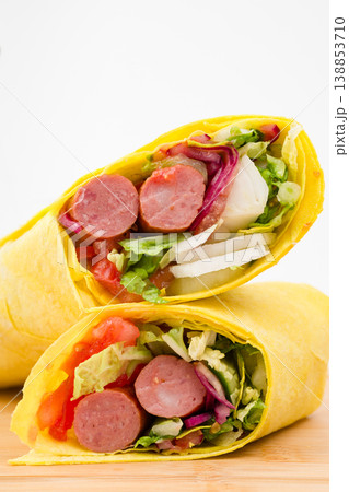 Delicious and colorful wrap filled with savory sausages, fresh vegetables, and vibrant greens, perfect for a quick meal or picnic delight any time of day Delicious and colorful wrap filled with savory sausages, fresh vegetables, and vibrant greens, perfect for a quick meal or picnic delight any time of day 138853710