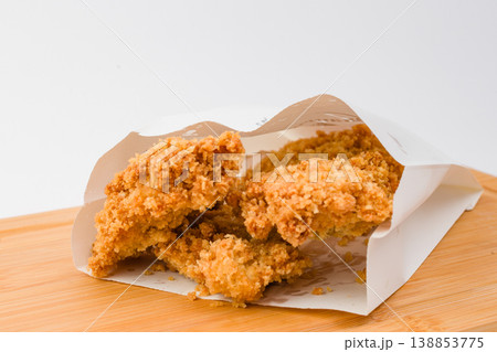 Crispy golden fried chicken pieces served in a stylish paper wrap on a wooden platter, perfect for a delightful snack or meal anytime 138853775