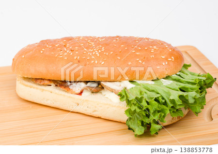 Delicious sandwich with fresh lettuce and savory fillings on a wooden board, perfect for a tasty lunch or snack anytime Delicious sandwich with fresh lettuce and savory fillings on a wooden board, perfect for a tasty lunch or snack anytime 138853778