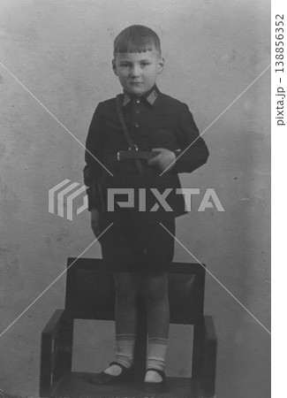 Vintage boy in school uniform standing on chair studio portrait 138856352