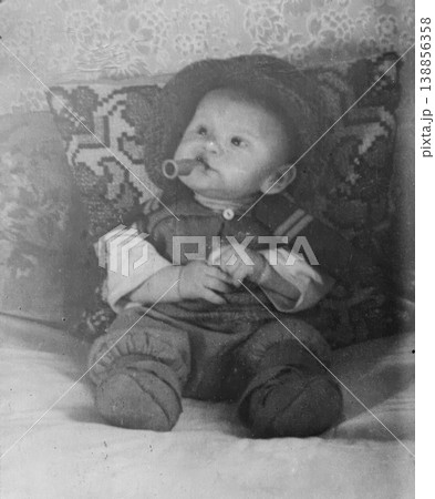 Vintage baby with pacifier sitting on embroidered pillow 1950s 138856358