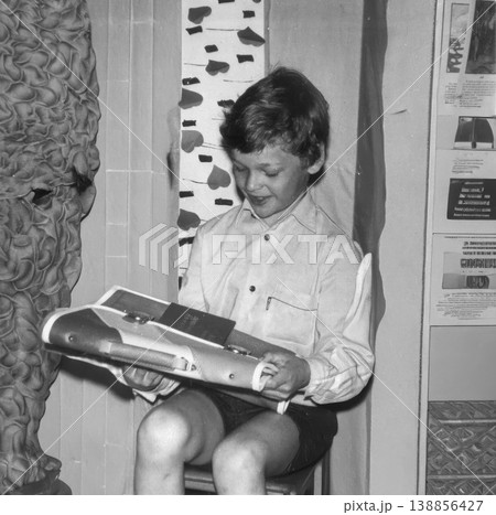 Boy sitting indoors holding school briefcase 1980s Boy sitting indoors holding school briefcase 1980s 138856427