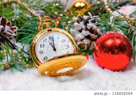 A vintage clock in the snow against the background of a Christmas tree and a garland 138856564