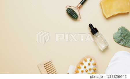 Beauty care arrangement featuring marble roller, gua sha, wooden body brush, facial cream and serum for natural skincare routine 138856645