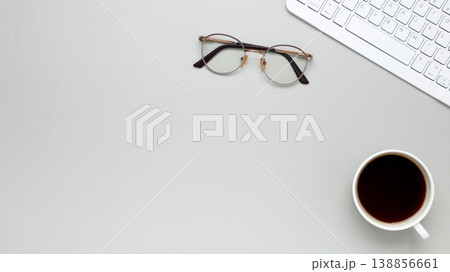 Minimal morning workspace with coffee cup, keyboard, and glasses fostering focused atmosphere 138856661