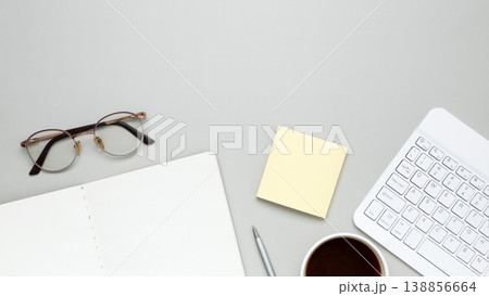 Organized workspace featuring keyboard, glasses, notebook, and stationery supporting productive workflow 138856664