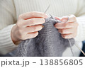 Hands of a woman in a white sweater crafting cozy fabric with knitting needles 138856805