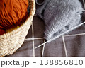 Knitted handmade fabric resting on basket filled with colorful yarn for craft project 138856810