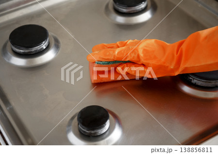 Woman wipes washed clean gas stove with sponge in kitchen Woman wipes washed clean gas stove with sponge in kitchen 138856811