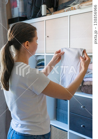 Woman organizing fresh laundry in closet, spring cleaning at home. Woman organizing fresh laundry in closet, spring cleaning at home. 138856966