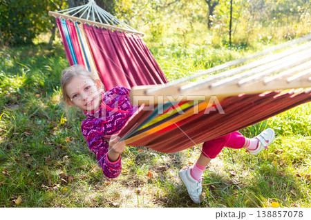 Girl Enjoys Swinging in a Hammock Outdoors During a Sunny Day in a Garden Setting Girl Enjoys Swinging in a Hammock Outdoors During a Sunny Day in a Garden Setting 138857078