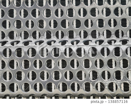 Texture of a metal grate showing circular holes arranged in a repeating pattern with a smooth surface 138857116