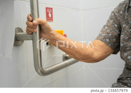 Asian elderly woman use toilet security support rail in bathroom. Asian elderly woman use toilet security support rail in bathroom. 138857979