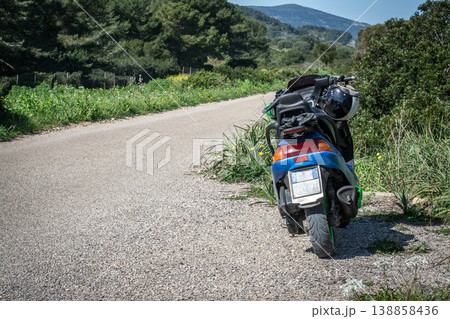 Motor scooter parked on the edge of an empty road Motor scooter parked on the edge of an empty road 138858436