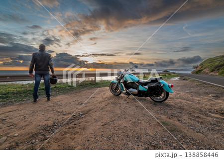 Biker standing by a classic motorcycle by the sea 138858446
