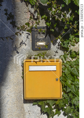 Yellow mailbox and doorbell on stone wall with ivy Yellow mailbox and doorbell on stone wall with ivy 138859213