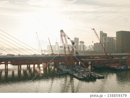 Aerial view of bridge sections being dismantled with a large crane over a river 138859379