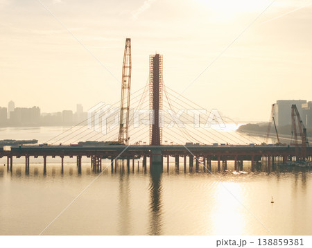 Aerial view of bridge sections being dismantled with a large crane over a river 138859381