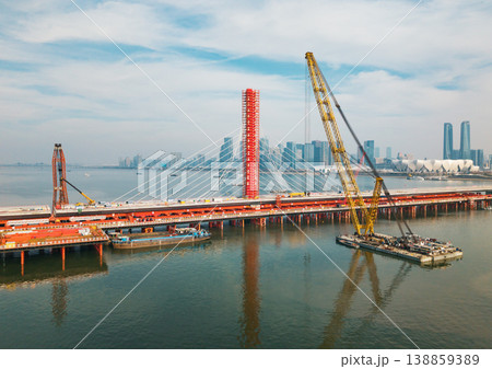 Aerial view of a large bridge over the river is in the process of being dismantled using cranes. Aerial view of a large bridge over the river is in the process of being dismantled using cranes. 138859389