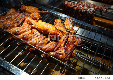 Grilled Chicken Wings on a Rack at a Vibrant Asian Night Food Street Market in China Grilled Chicken Wings on a Rack at a Vibrant Asian Night Food Street Market in China 138859488